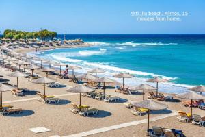 a beach with many chairs and umbrellas and the ocean at Comfortable Apartment in Athens Kallithea in Athens