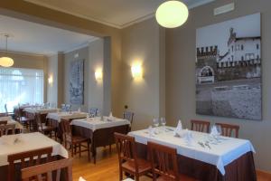 Albergo Ristorante Belvedere في تيني: مطعم بطاولات وكراسي بيضاء وصورة على الحائط