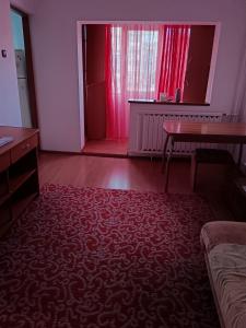 a living room with a table and a red carpet at Apartament 1 camera zona liniștită in Drobeta-Turnu Severin +4 photos