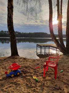 a beach with a red chair and a red chair in the sand at Dom nad Jeziorem Bory Tucholskie Pomost Łódka in Cierplewo