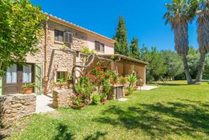 ein Steinhaus mit Blumen im Hof in der Unterkunft Can Ferrer in Pollença