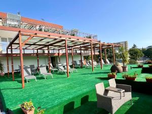 d'une terrasse avec des chaises et des tables sur une pelouse verdoyante. dans l'établissement BSA Gradina Hotel - All Inclusive & Private Beach, aux Sables d'or