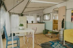 a kitchen with a table and chairs and a refrigerator at Bueno Campers - lux przyczepy na wynajem in Jastarnia