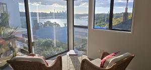a room with two chairs in front of a large window at 2 Bedroom home, City and Sea Views in Auckland