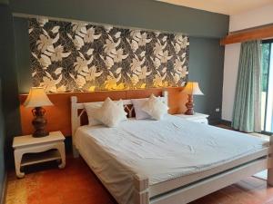 a bedroom with a white bed with a floral wallpaper at Bhumiyama Plus in Ko Chang