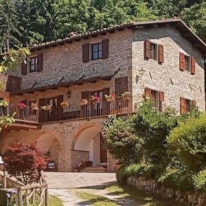 una casa de piedra con un balcón con flores. en LE PIANACCE - Appartamento per vacanze, en Castiglione di Garfagnana