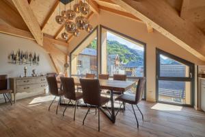a dining room with a table and chairs and large windows at La Grange in LʼHuez