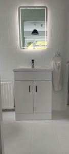 Baño blanco con lavabo y espejo en Riverfield Bed and Breakfast en Gorey