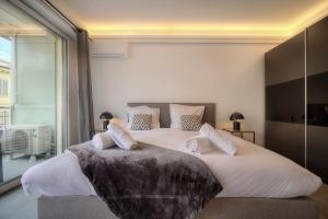 a bedroom with two beds and a large window at Cannes Luxury Rental - Stunning apartment with terrace to rent Grand Hotel in Cannes +15 photos