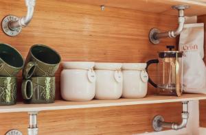 a shelf with a bunch of cups on it at Leto Shepherds Hut By Airpremier in Alfriston +6 photos