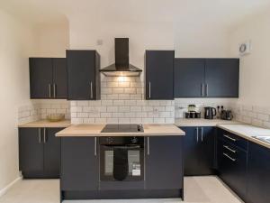 a kitchen with black cabinets and a stove top oven at Recently renovated stylish home parking Pass the Keys in Bishop Auckland