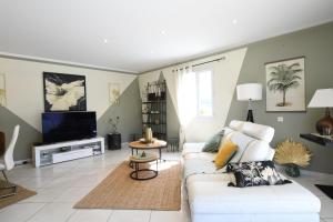a living room with a white couch and a tv at Entre les Alpilles, la Mer, la Camargue, à huit kilomètres de ARLES ,Villa des jasmins ,piscine,3 chambres ,climatisation, wifi fibre in Raphèle