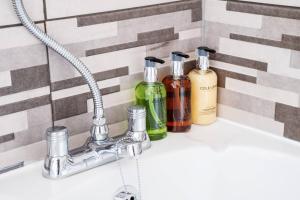 a bathroom sink with three bottles of soap at Recently renovated stylish home parking Pass the Keys in Bishop Auckland +33 photos