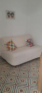 a white couch with two pillows on a carpet at Casa Vacanze Altea in Santa Flavia