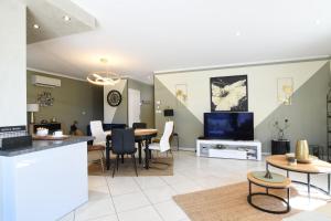 a living room with a dining table and a tv at Entre les Alpilles, la Mer, la Camargue, à huit kilomètres de ARLES ,Villa des jasmins ,piscine,3 chambres ,climatisation, wifi fibre in Raphèle
