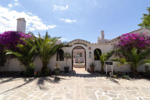 Un bâtiment blanc avec des palmiers et des fleurs violettes dans l'établissement La Casa del Burro, à Nerja