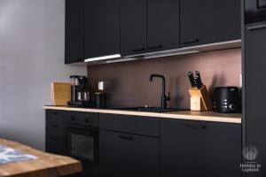 Una cocina con gabinetes negros y encimera. en Holiday in Lapland - LeviLeijona, en Levi