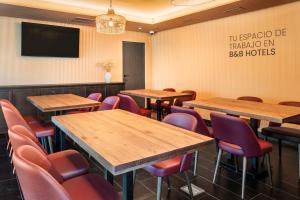 une salle de conférence avec des tables et des chaises en bois dans l'établissement B&B HOTEL Écija, à Écija