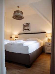 1 dormitorio con 1 cama grande con sábanas blancas en Steilufer Appartments, en Timmendorfer Strand