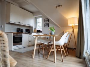 uma cozinha com uma mesa de madeira e cadeiras brancas em Steilufer Appartments em Timmendorfer Strand