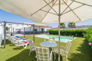 a group of tables and chairs under an umbrella next to a pool at Casa rural Villa Gordito in La Lantejuela