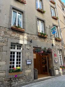 - un bâtiment en pierre avec des fenêtres et des fleurs sur la porte dans l'établissement Hotel des Abers, à Saint-Malo