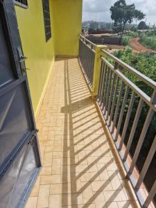 un balcon d'un bâtiment jaune avec une balustrade dans l'établissement Bel Appartement meublé à Bafoussam, à Bafoussam
