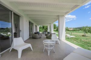 an outdoor patio with white chairs and a table at Villa DEG Vista Mare San Teodoro Puntaldia in San Teodoro