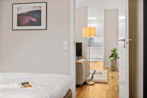 a white bedroom with a bed and a living room at Liseberg Södra in Gothenburg