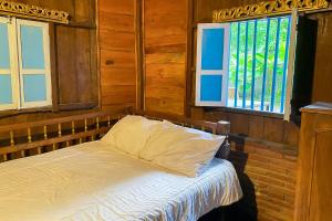 Cama en habitación con 2 ventanas en Lembah Mbalong Resort Mitra RedDoorz Near Exit Tol Singosari en Blimbing