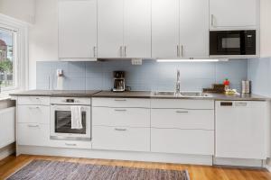 a white kitchen with white cabinets and a sink at Liseberg Södra in Gothenburg +23 photos