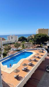 basen z leżakami i parasolami w budynku w obiekcie Cielomar Benalmadena costa w mieście Benalmádena