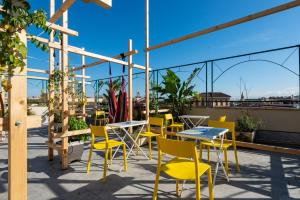 a patio with tables and yellow chairs on a roof at Ostello Bello Roma Colosseo in Rome +52 photos