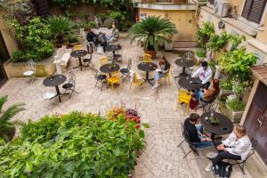 un gruppo di persone seduti ai tavoli in un giardino di Ostello Bello Roma Colosseo a Roma