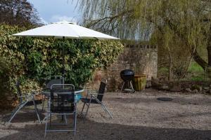 deux chaises, un parasol et un barbecue dans l'établissement The Rookery Cottage - Newland, à Newland 5 autres photos