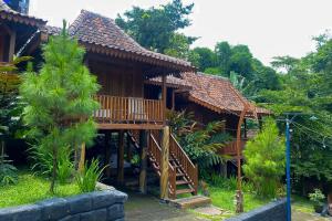una casa de madera con una escalera delante de ella en Lembah Mbalong Resort Mitra RedDoorz Near Exit Tol Singosari en Blimbing