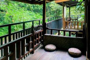 un porche con 2 sillas y una valla de madera en Lembah Mbalong Resort Mitra RedDoorz Near Exit Tol Singosari en Blimbing
