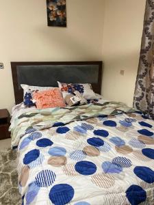 a bed with a blue and white comforter on it at Villa de chez nous in North Legon