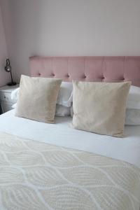 een wit bed met 2 kussens en een roze hoofdeinde bij Restful Rentals in Aberdeen