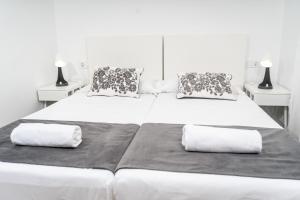 two beds in a white room with two pillows at Apartamentos Turísticos Teatro Romano by CartagenaSpain in Cartagena