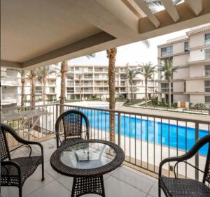 a balcony with a table and chairs and a swimming pool at Marassi Marina in El Alamein