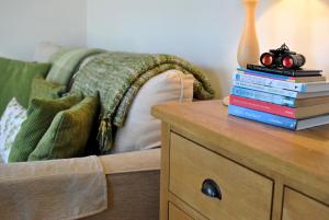 ein Stapel Bücher auf einem Nachttisch neben einem Bett in der Unterkunft 2a Rose St- cosy coastal cottage Fife in Saint Monance