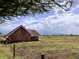 an old barn in a field with a fence at Kilimanjaro view cabin-Amboseli in Oloitokitok 