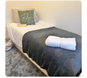 a bed with a black blanket and pillows on it at The Hideout in Trearddur
