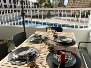 a table with plates and wine glasses on a balcony at Patio Canario * Beach Escape / 2 rooms, 2 terraces & pool in Arona