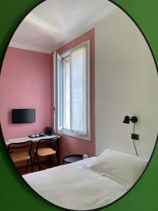 una camera da letto con un letto, una scrivania e uno specchio di Studio-Majno a Milano