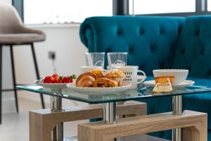 a glass table with a tray of pastries and fruit at Heathrow Family Apartments in Sunbury Common +20 photos
