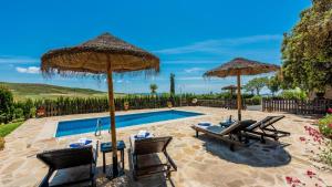 a swimming pool with two umbrellas and two chairs and a table at Casa Tere Antequera - La Higuera by Ruralidays in Antequera
