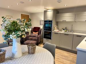 Wren is a stunning 1-Bed Cottage near Coleford في كول فورد: مطبخ مع طاولة مع إناء من الزهور