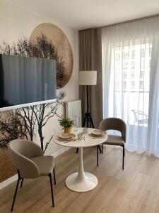 Una sala de estar con una mesa y sillas y un televisor. en TOMALE-AMT Apartamenty Kasprowicza Kołobrzeg - basen, jacuzzi, sauna, siłownia w cenie apartamentu, en Kołobrzeg